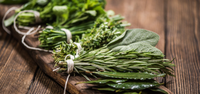 Imagem de maços verdes de temperos orgânicos, como manjericão, salsa e coentro, dispostos em uma tábua de madeira