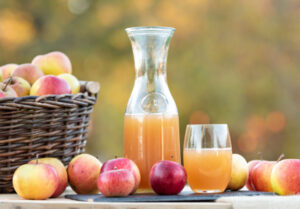 Sucos refrescantes de maçã orgânica em copos rodeados por maçãs frescas.