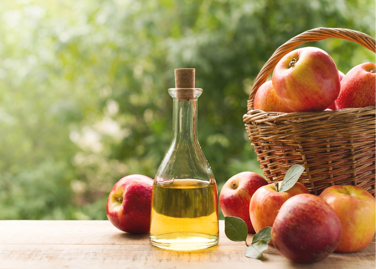Vinagre de maçã orgânico em garrafa de vidro com maçãs ao fundo