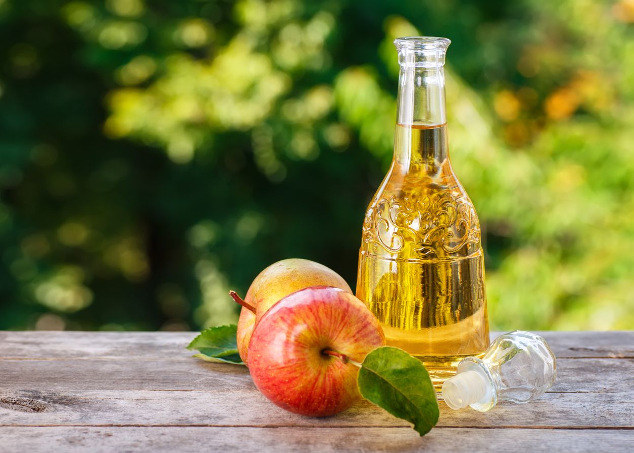 Vinagre de maçã orgânico e maçãs frescas em mesa de madeira