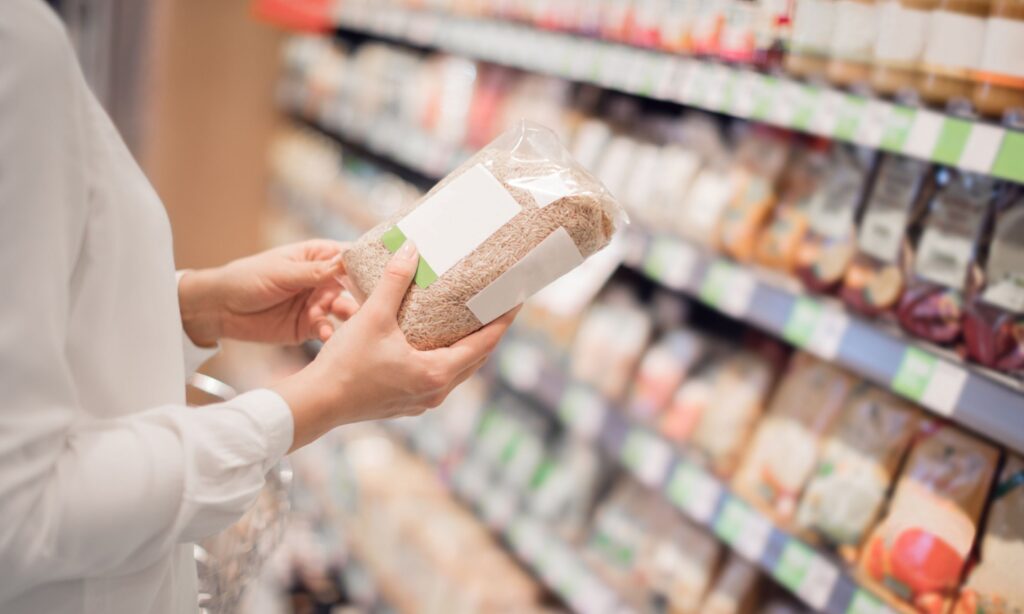 Escolhendo Produtos Orgânicos no Supermercado - Uma pessoa examina a embalagem de um produto orgânico nas prateleiras.